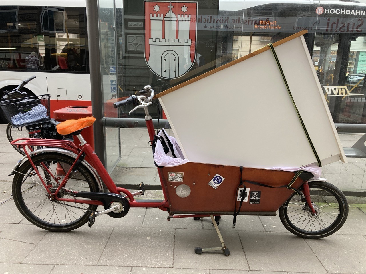 Langes Bakfiets Lastenrad mit großer, weißer Holz-Kommode in der Transportkiste